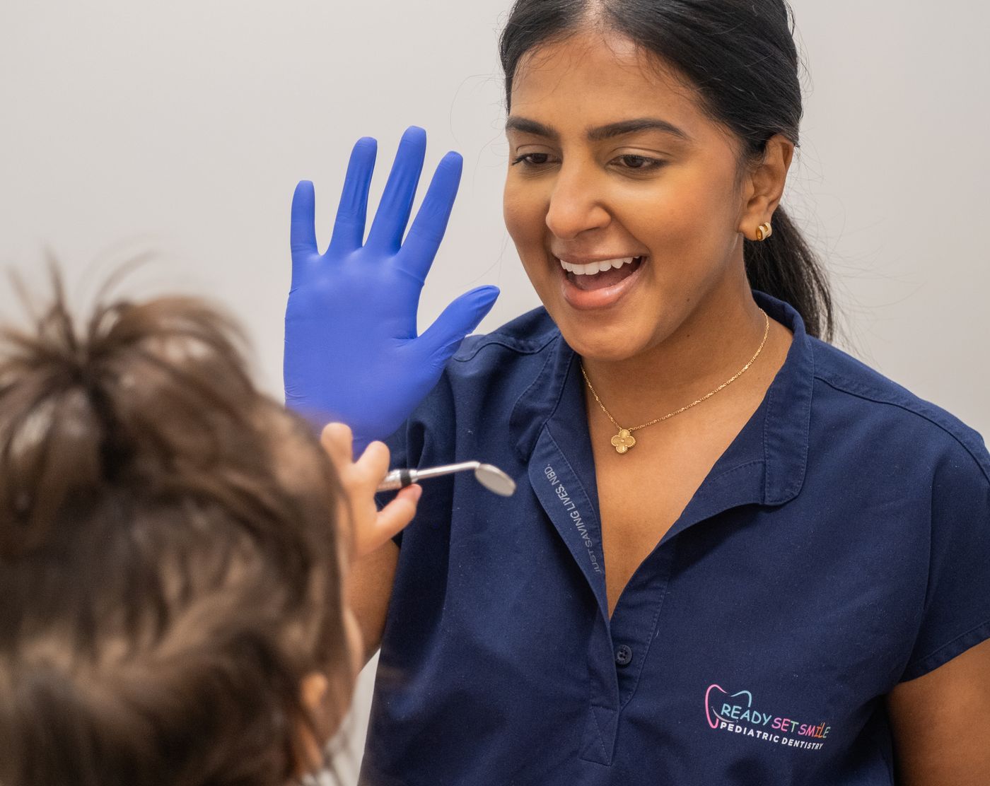 Dr. Amanda Brijlall of Ready Set Smile high-fiving a young patient